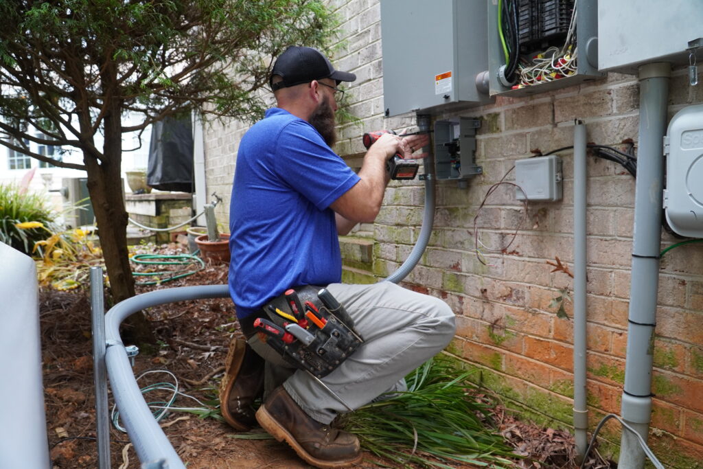 Durham electrician working on a power panel outside